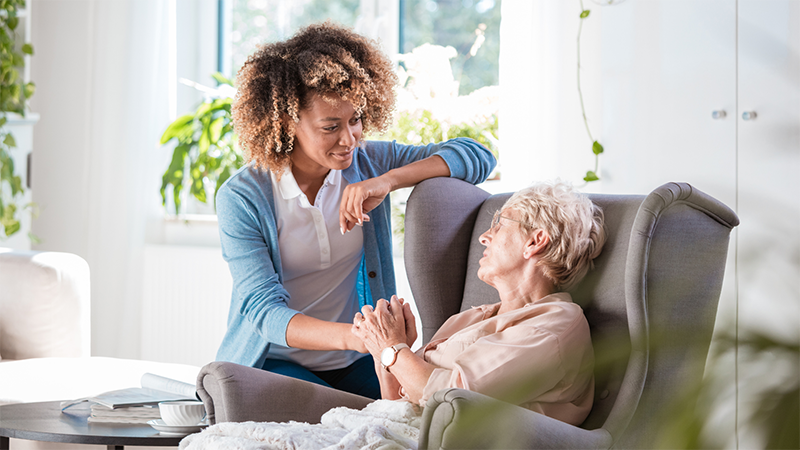 Frail elderly person in wheelchair with caregiver