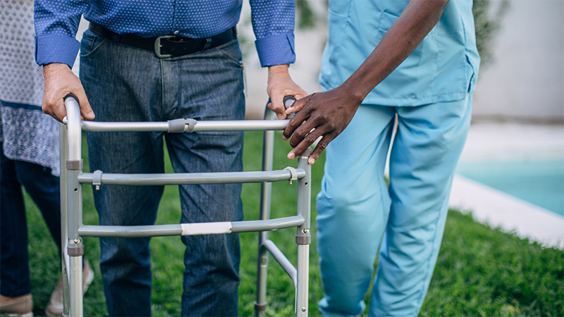 Frail elderly person in wheelchair with caregiver